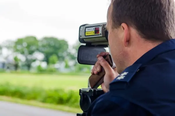 Ein Polizist misst per Laser zu schnell fahrende Fahrzeuge und erstellt dabei Blitzerfotos.